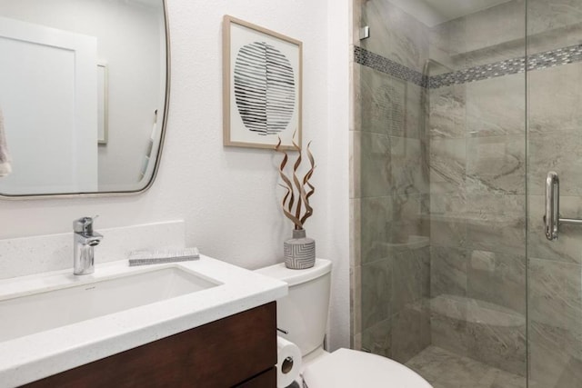 bathroom featuring toilet, vanity, and an enclosed shower