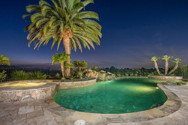 pool at dusk with an in ground hot tub and pool water feature