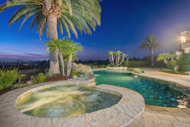 pool at dusk with an in ground hot tub and pool water feature