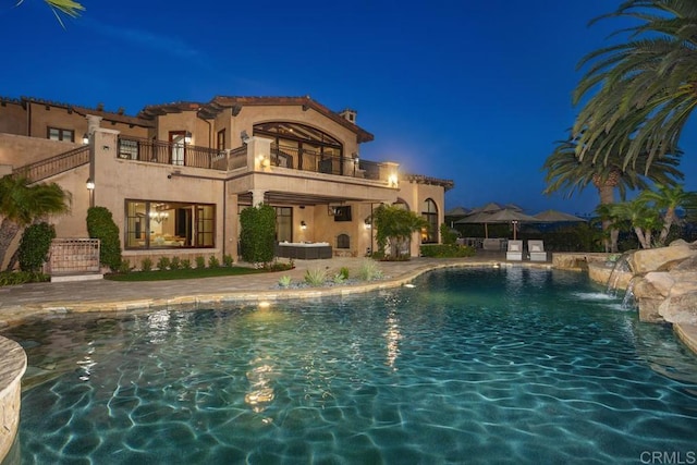 pool at twilight featuring pool water feature and a patio area