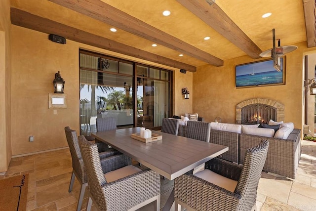 dining space featuring beamed ceiling and an outdoor stone fireplace