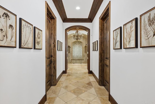 hall with ornamental molding and an inviting chandelier