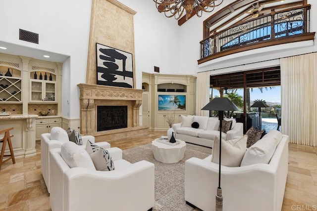 living room with an inviting chandelier, a tile fireplace, and a high ceiling