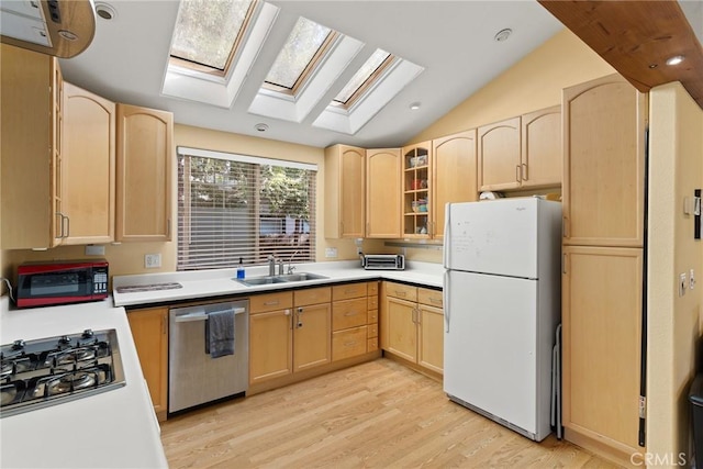 kitchen with vaulted ceiling with skylight, stainless steel appliances, light wood-type flooring, and light brown cabinets