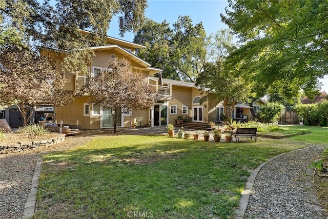 rear view of property featuring a balcony and a yard