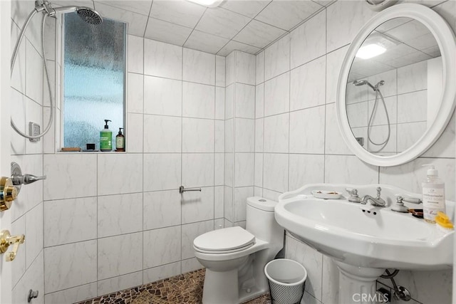 bathroom with a shower, tile walls, and toilet