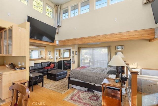 bedroom featuring a towering ceiling and light hardwood / wood-style floors