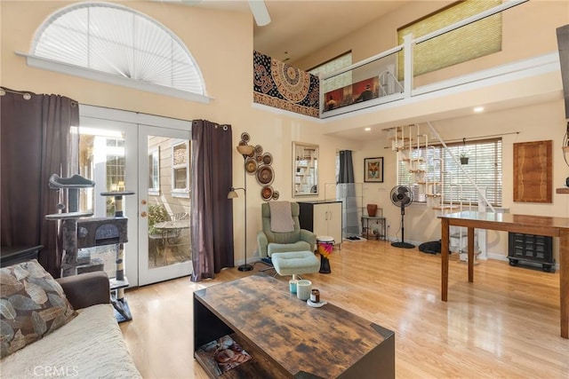 living room featuring light hardwood / wood-style floors, a high ceiling, and french doors