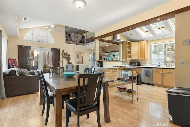 dining room with french doors, sink, a skylight, ceiling fan, and light hardwood / wood-style floors