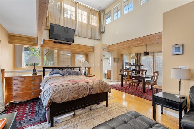 bedroom featuring hardwood / wood-style flooring, a high ceiling, and multiple windows