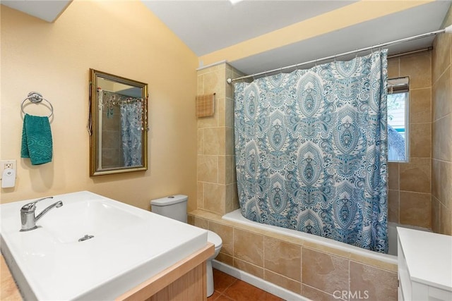 full bathroom featuring vanity, shower / bath combination with curtain, vaulted ceiling, tile patterned flooring, and toilet