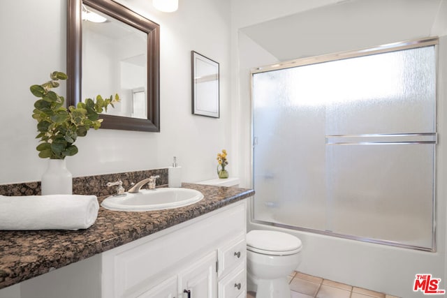 full bathroom featuring bath / shower combo with glass door, toilet, vanity, and tile patterned flooring