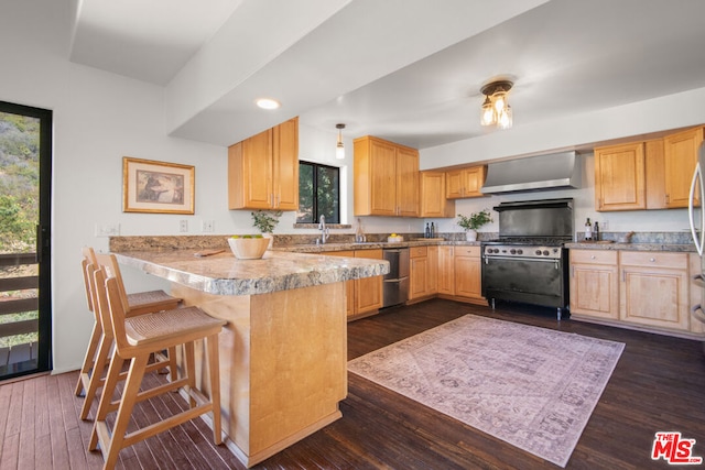 kitchen with wall chimney exhaust hood, black gas range oven, dark hardwood / wood-style floors, kitchen peninsula, and a breakfast bar