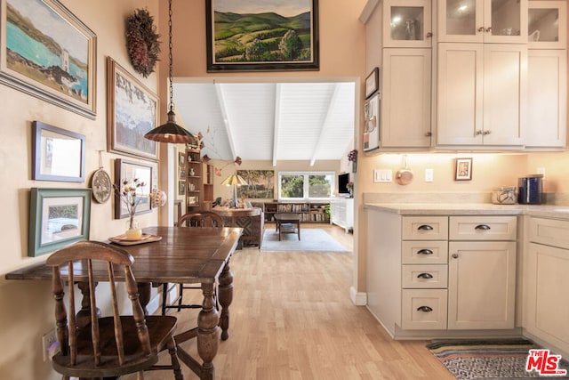 dining area featuring light hardwood / wood-style floors and vaulted ceiling with beams