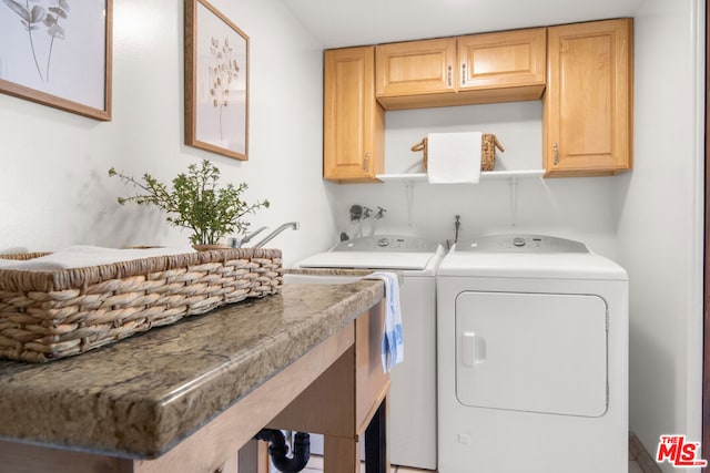 clothes washing area with separate washer and dryer and cabinets