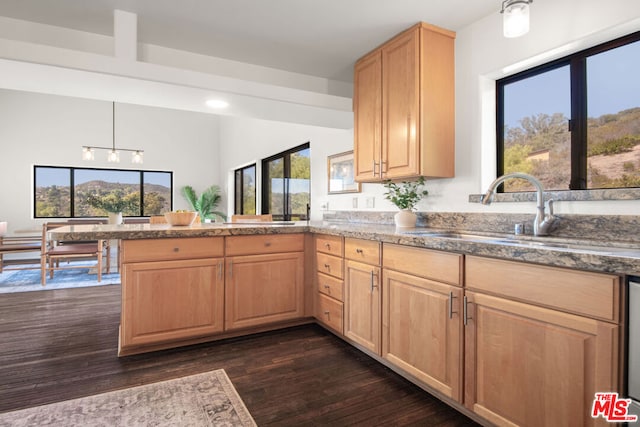 kitchen featuring kitchen peninsula, sink, hanging light fixtures, light brown cabinetry, and dark hardwood / wood-style flooring