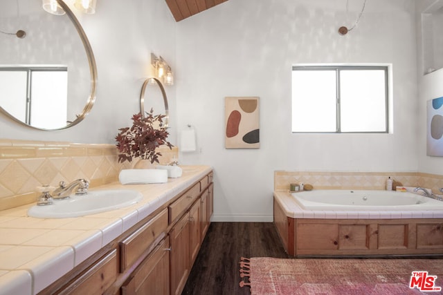 bathroom featuring a tub, hardwood / wood-style floors, vanity, and lofted ceiling