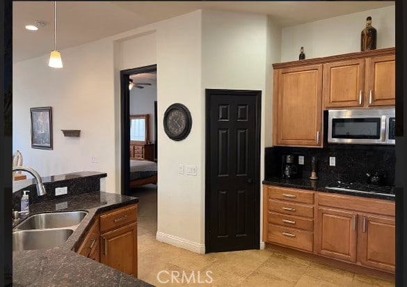 kitchen with backsplash, sink, hanging light fixtures, light tile patterned floors, and gas cooktop