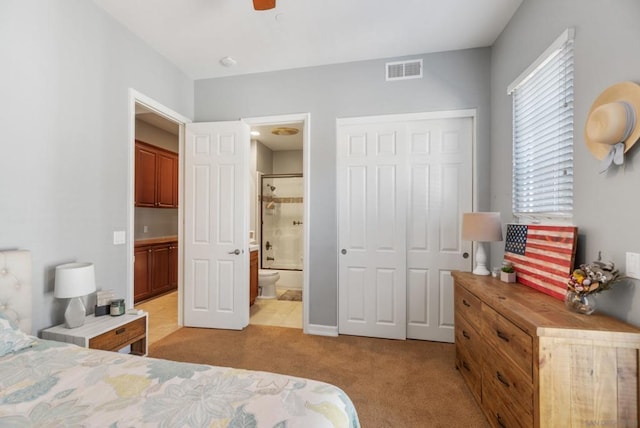 carpeted bedroom featuring ceiling fan, a closet, and ensuite bath