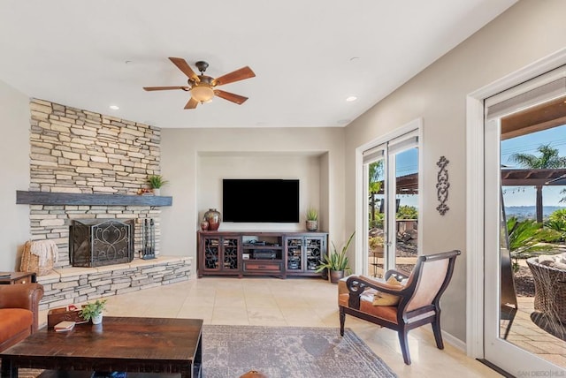 tiled living room featuring a stone fireplace and ceiling fan