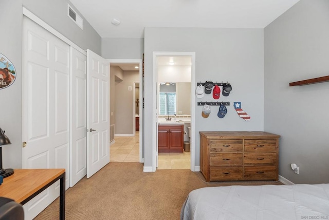 bedroom featuring light carpet, ensuite bath, a closet, and sink