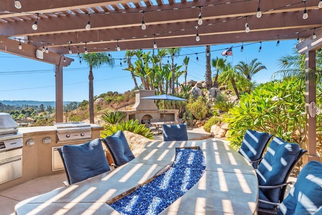 view of patio with an outdoor stone fireplace, a grill, and an outdoor kitchen