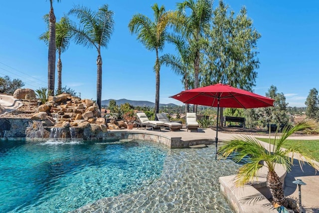 view of pool featuring a mountain view, pool water feature, and a patio