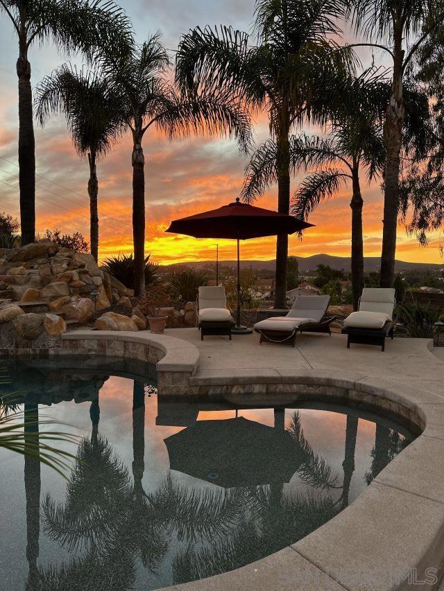 pool at dusk featuring a patio