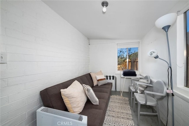 living room featuring lofted ceiling and brick wall