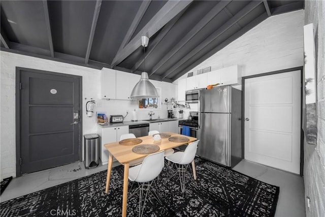 kitchen with lofted ceiling with beams, white cabinetry, sink, and stainless steel appliances