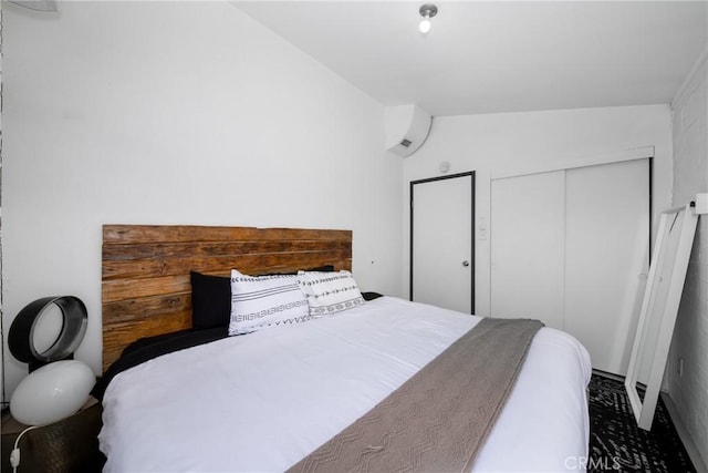 bedroom with a wall mounted AC, vaulted ceiling, and a closet