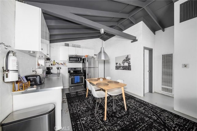 kitchen featuring beam ceiling, white cabinetry, hanging light fixtures, concrete flooring, and appliances with stainless steel finishes