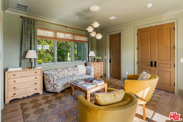 living area with hardwood / wood-style flooring and crown molding