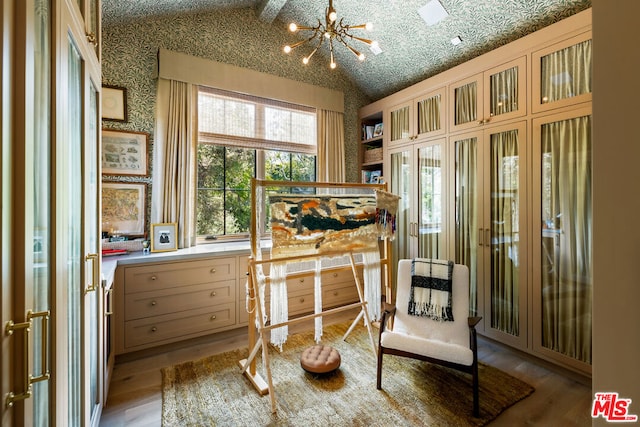 living area featuring a chandelier, lofted ceiling with beams, and light wood-type flooring