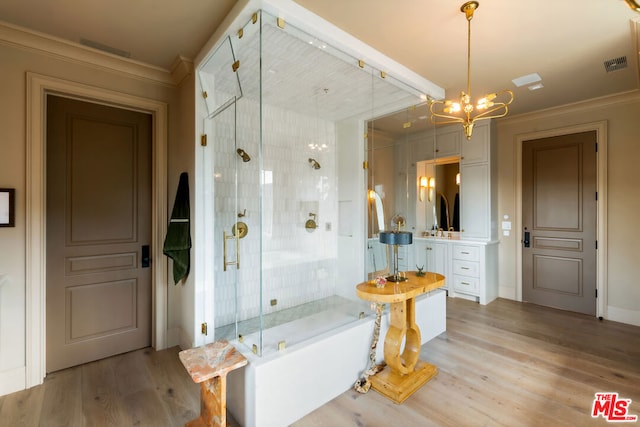 bathroom with an inviting chandelier, wood-type flooring, separate shower and tub, ornamental molding, and vanity