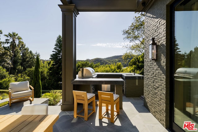 view of patio / terrace featuring a mountain view, sink, and a grill