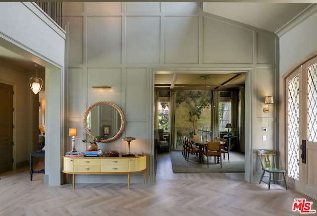 foyer entrance featuring crown molding, a high ceiling, and light parquet flooring