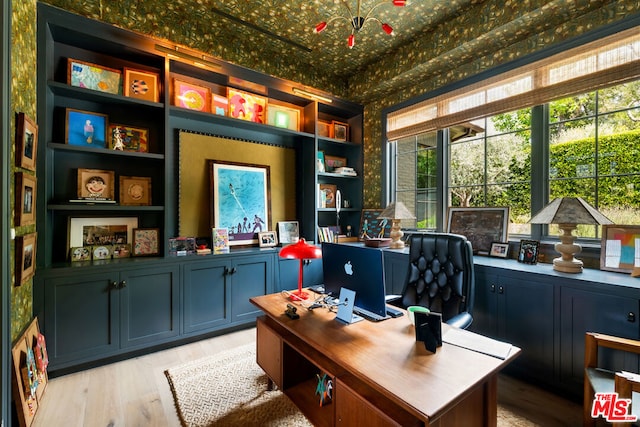 office area with built in shelves and light hardwood / wood-style flooring