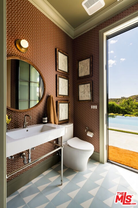 bathroom with crown molding, toilet, and a water view