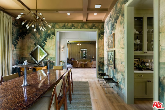 dining space with light hardwood / wood-style floors, coffered ceiling, a notable chandelier, and beam ceiling