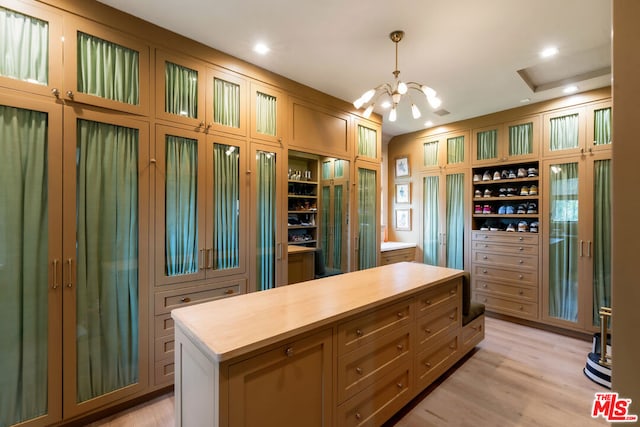 spacious closet with light hardwood / wood-style flooring and a chandelier