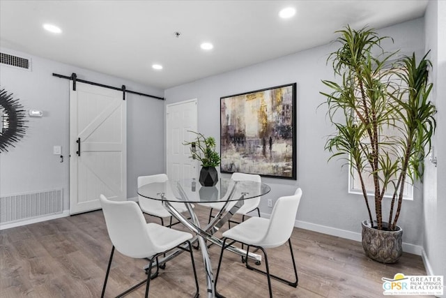 dining room with a barn door and wood-type flooring