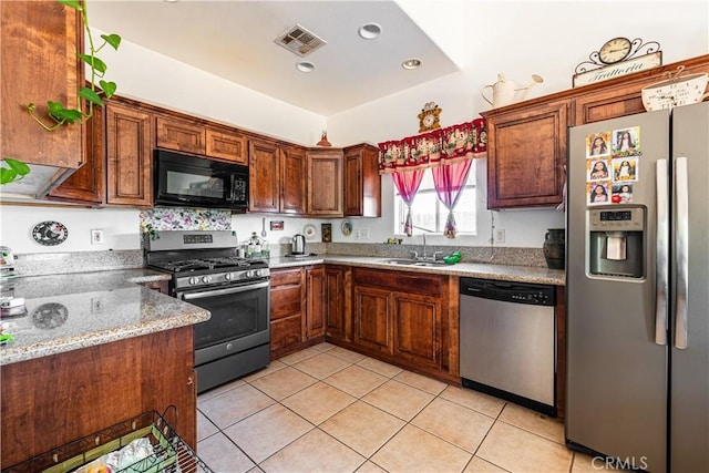 kitchen with light tile patterned flooring, sink, light stone countertops, and stainless steel appliances