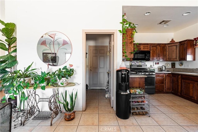 kitchen with gas range, dark brown cabinetry, and light tile patterned flooring