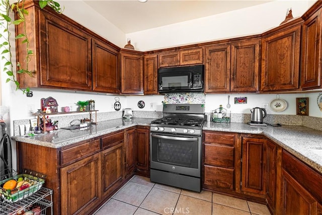 kitchen with light stone countertops, light tile patterned flooring, and stainless steel range with gas stovetop