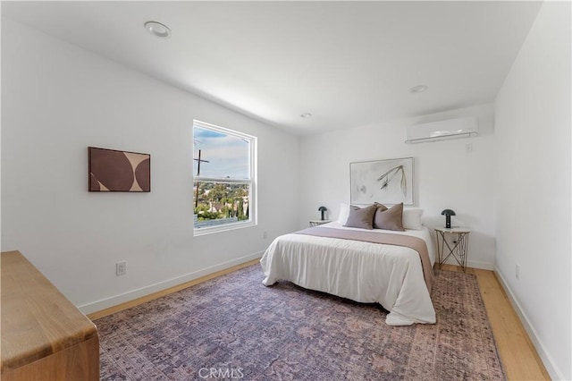 bedroom featuring a wall mounted air conditioner and wood-type flooring