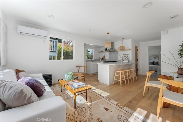 living room with a wall mounted air conditioner and light hardwood / wood-style flooring