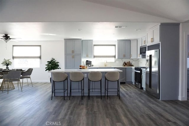 kitchen featuring appliances with stainless steel finishes, dark hardwood / wood-style flooring, vaulted ceiling, and plenty of natural light