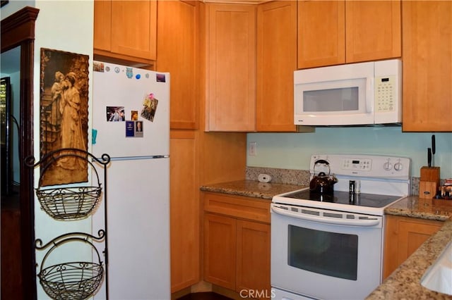 kitchen featuring light stone counters and white appliances