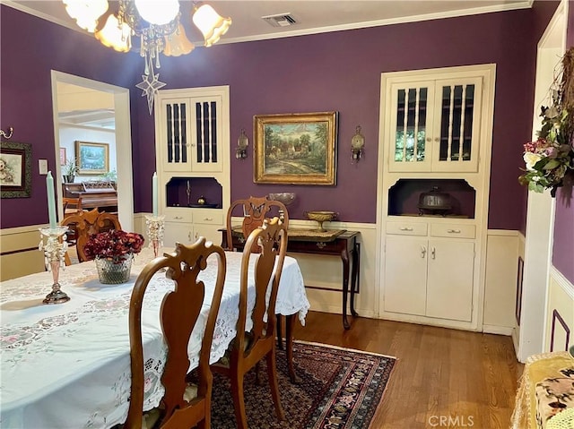 dining space with hardwood / wood-style floors, a chandelier, and ornamental molding